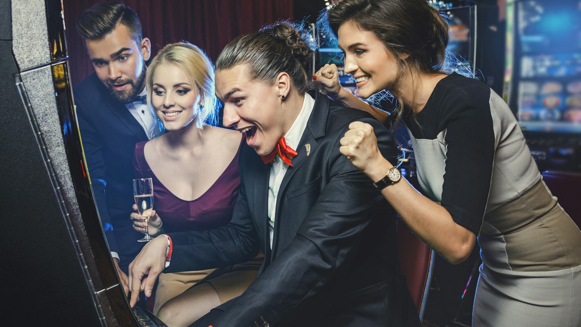 Group of friends playing slot machines in casino